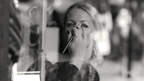 A woman getting makeup put on her in a salon. 