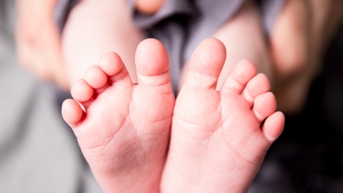 A person holding the tiny feet of a baby.