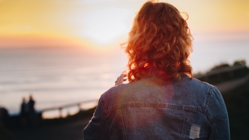 A woman looking at sunset over a body of water.