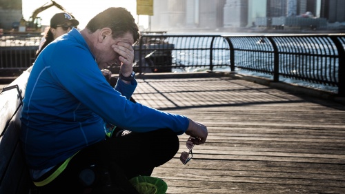 A man sitting on a dock with the water near by. 