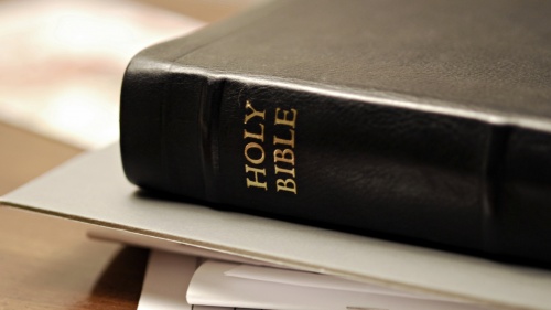 A Bible sitting on top of some notebooks and paper.