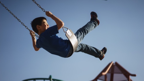 A boy swinging on a playground swing.
