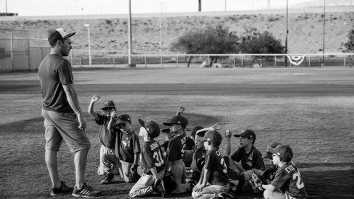 A little league baseball team look up at their coach.