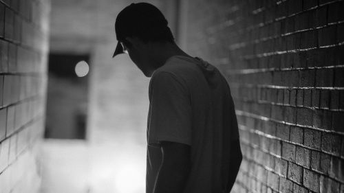 A man walking in a hallway surrounded by brick walls.