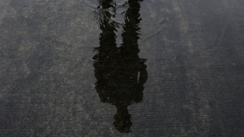 A person's shadow in shallow pool of water.