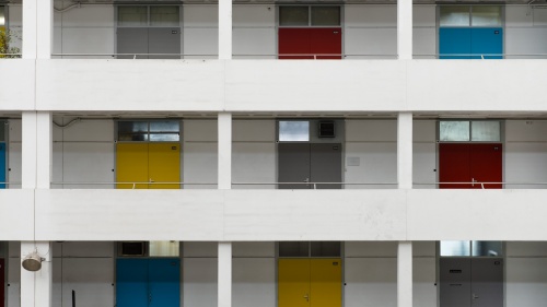 Outside of building with several floors featuring different colored doors.