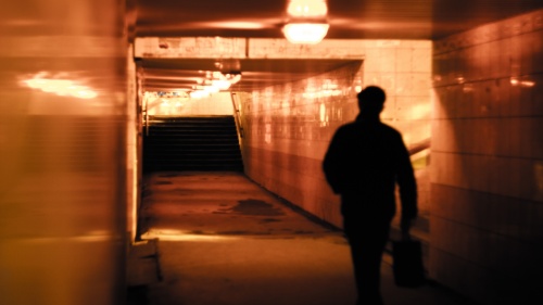 A man walking down a tunnel hallway.