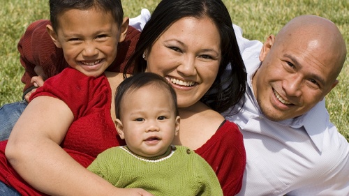 A family lying down on a blanket.