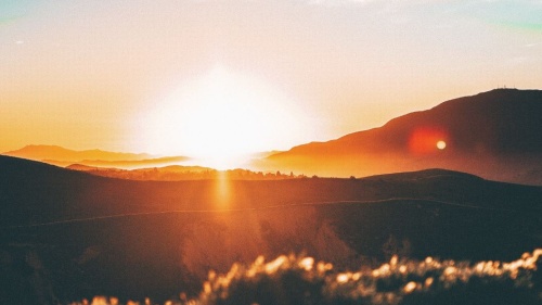 Sun rays shining over hills.