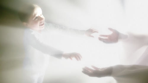 A photo illustration showing a person reaching for another person surrounded by bright lights.