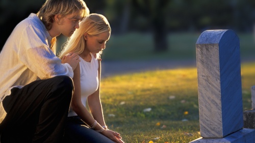 A young couple by a grave stone.