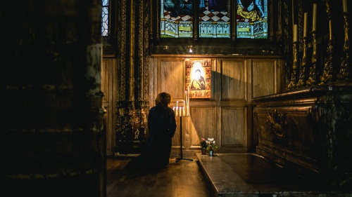 A woman praying to a painting hanging in a church.