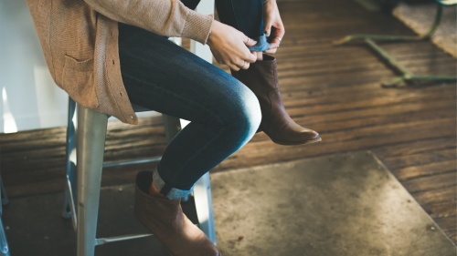 A woman sitting on a bench adjusting her shoes.