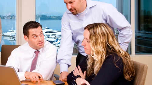 A group of people working together at a table using laptops.