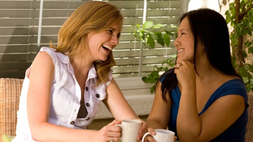 Two women laughing and talking together. 