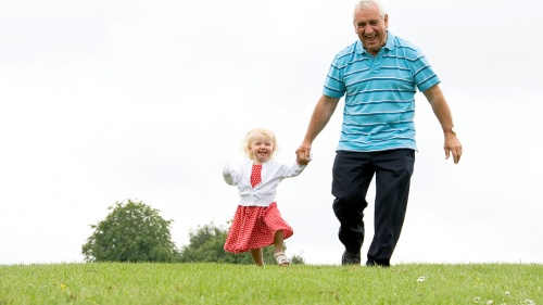 A grandfather holding his little grandaughter's hands.