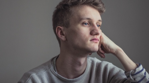 A young man resting his head on his hand.