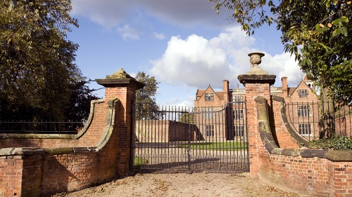 A big gate surrounding a large brick house.