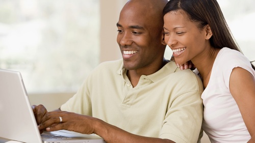 A young couple looking at a laptop computer.