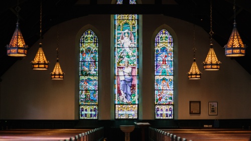 Inside a large church with stain glass windows.