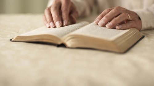 A person's hands on top of a Bible.