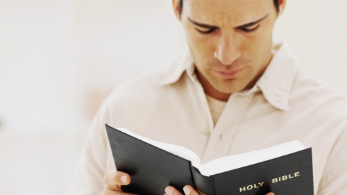 A man holding and reading a Bible.