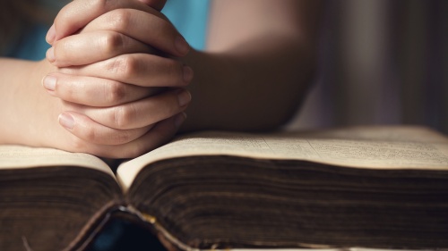 A person with their hands on top of a Bible.