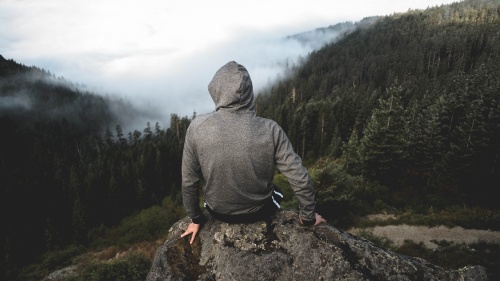 A person sitting on a rock looking over a valley.