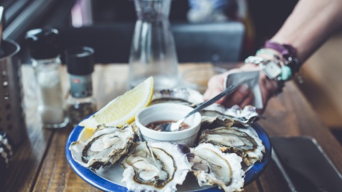 Raw oysters being served on a platter in a restaurant.