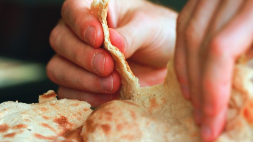 A person tearing unleavened bread.