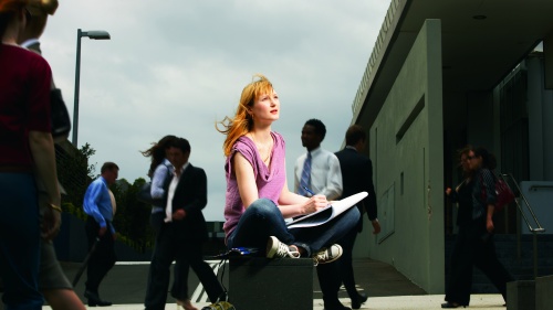 A woman sitting in a public place looking up.