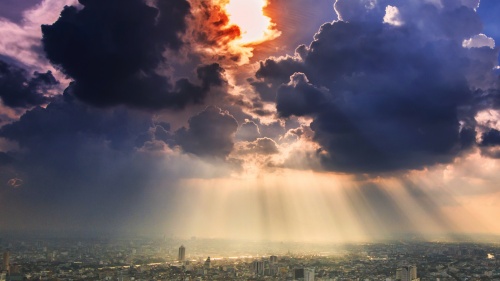 Sun rays and clouds over a big city.