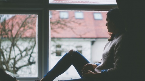 A young woman sitting by a window.