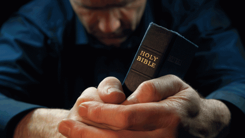 A man praying over his Bible