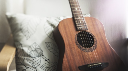 A guitar propped up against a chair.