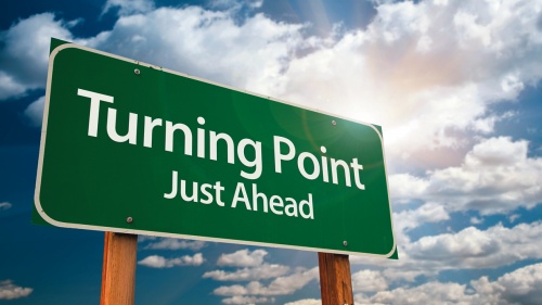 A green road sign with the words "Turning Point: Just Ahead".