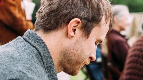 A man with his head down appearing to be grieving. 