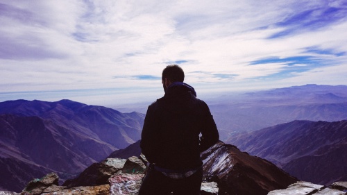 A man standing on top of a mountain peak.