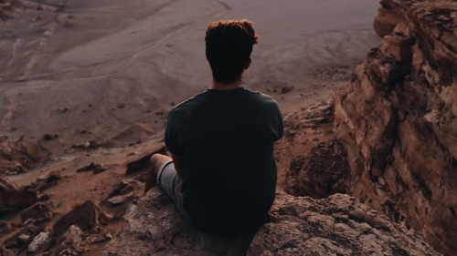 A young man sitting on a rock cliff