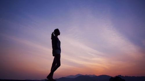 A woman with the a sunset sky in the background.