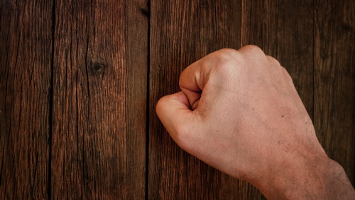 A close fist knocking on a door.