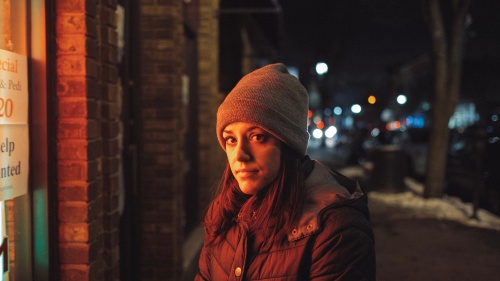 A young woman standing outside a store.