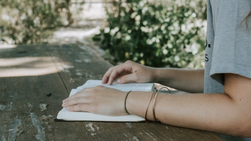 A young woman reading a Bible on a old table.