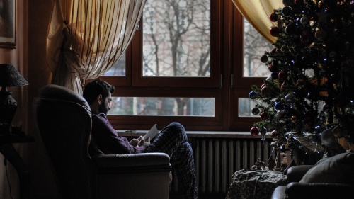 A man sitting in a chair across from a Christmas tree.