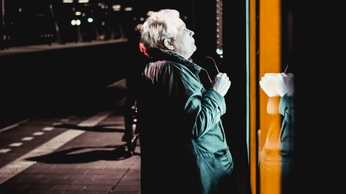 An older person looking into a store window at night.