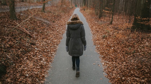 A woman walking on a paved path.