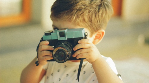 A little boy playing with a camera.