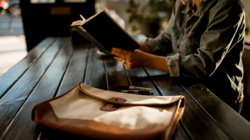 A woman reading a book at a table.