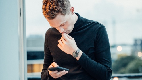 A young man looking down at his smartphone.