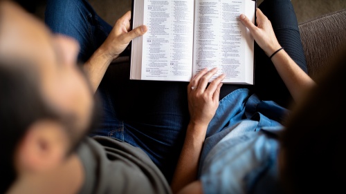 A man and woman holding a Bible together.